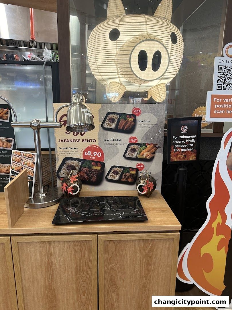 A display of Japanese bento boxes with prices and descriptions, featuring a pig lantern.