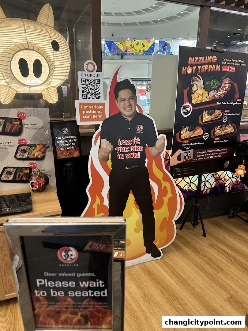Aburi-EN Changi City Point entrance with a cutout of a man and menu displays.