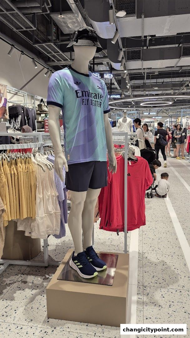Mannequin displays Adidas sportswear including a jersey, shorts, and sneakers in a retail store.