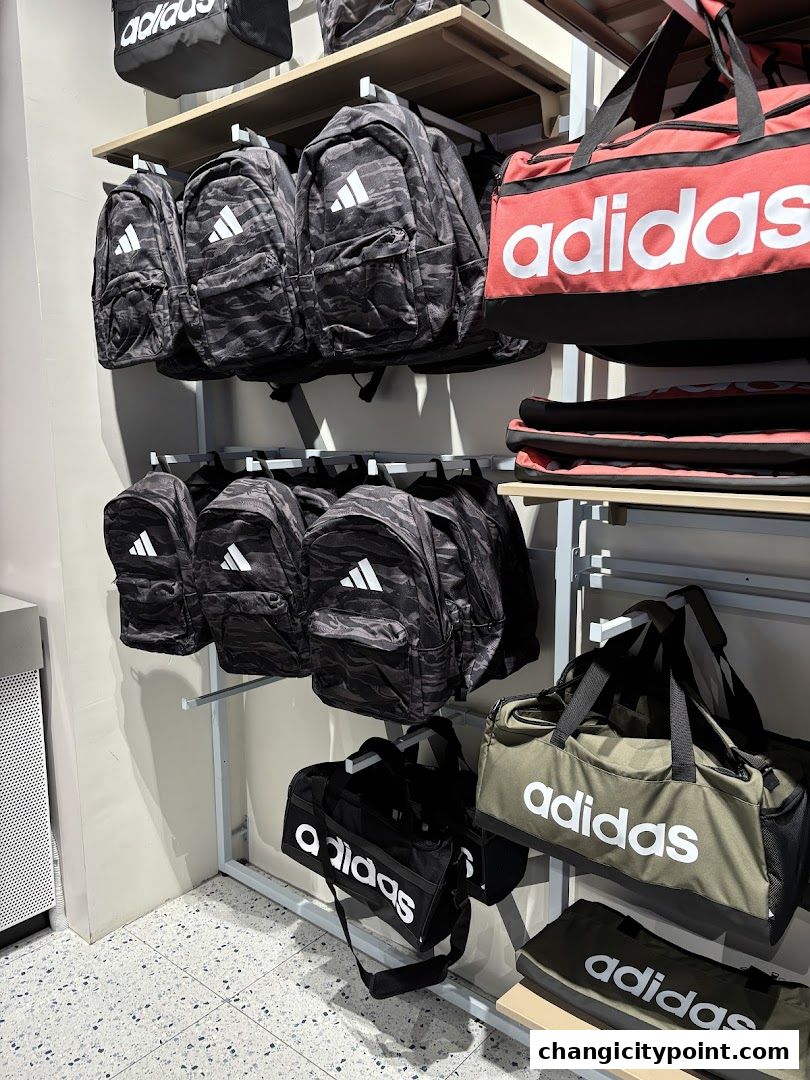 Adidas backpacks and duffel bags displayed on shelves in a retail store.