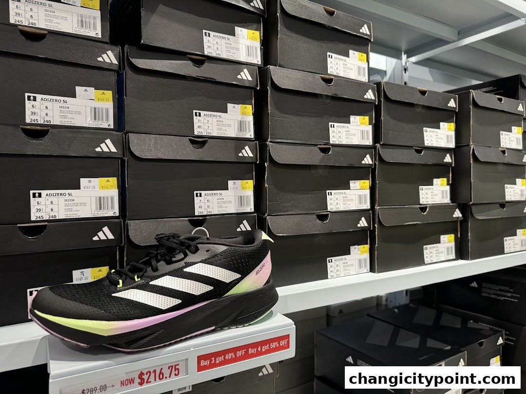 A display of Adidas shoe boxes stacked high, with a single running shoe in the foreground.