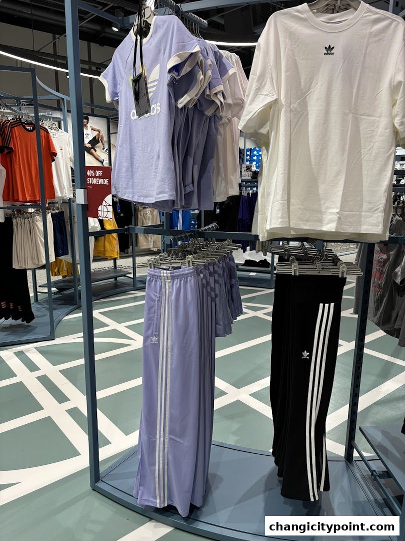 Adidas apparel including t-shirts and track pants displayed in a store.