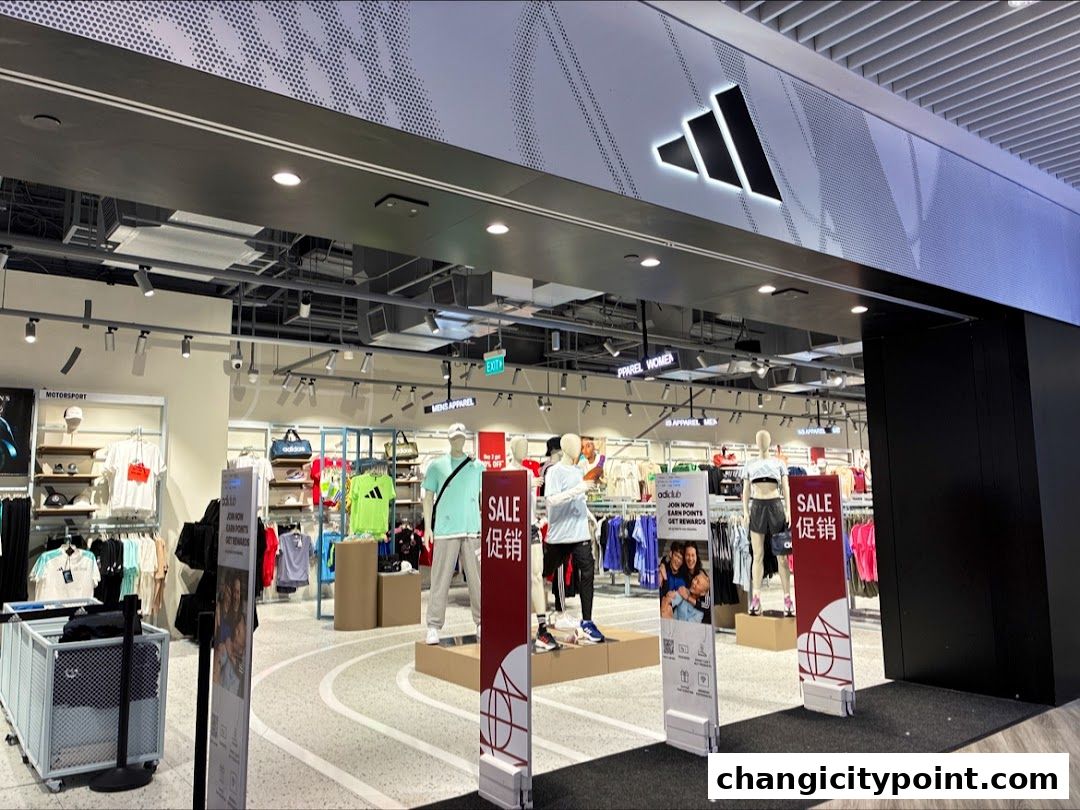 Entrance to an Adidas Factory Outlet store with apparel displays and sale signs.