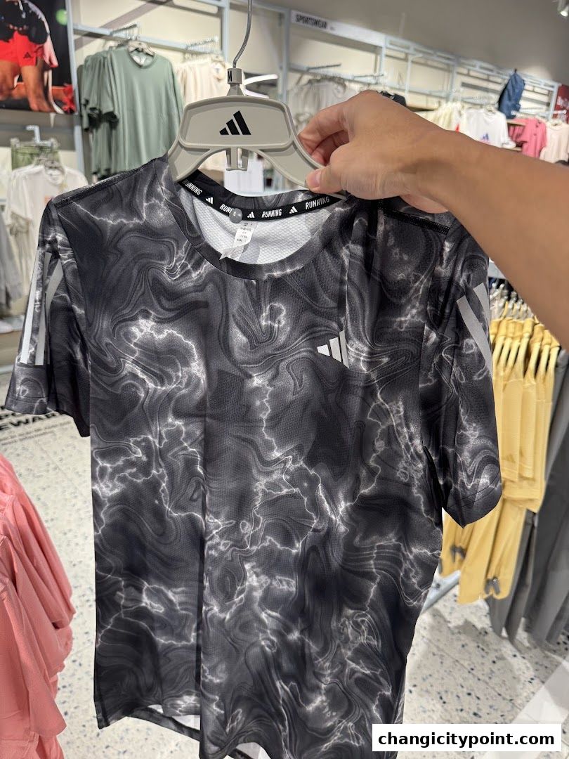 A person holds up a black and white marbled pattern Adidas running t-shirt.
