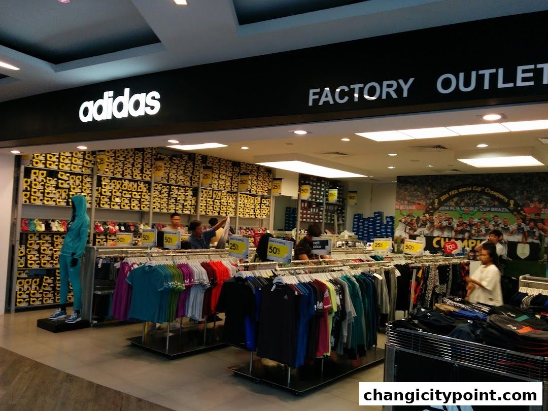 Interior view of an Adidas Factory Outlet store with clothing racks and shoe boxes.