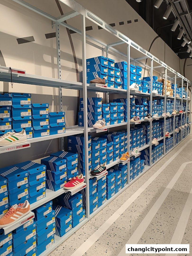 Shelves stocked with Adidas shoe boxes and display shoes in a retail store.