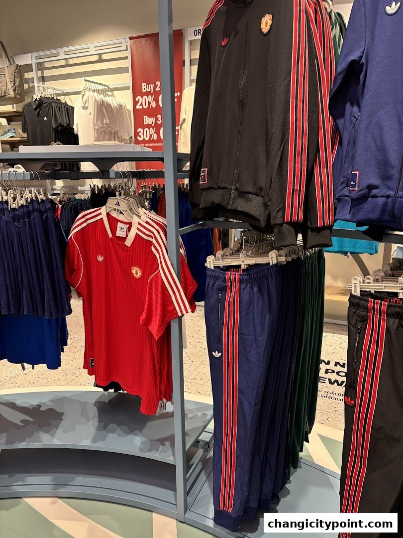 Adidas apparel including tracksuits and jerseys displayed on racks with sale signs.