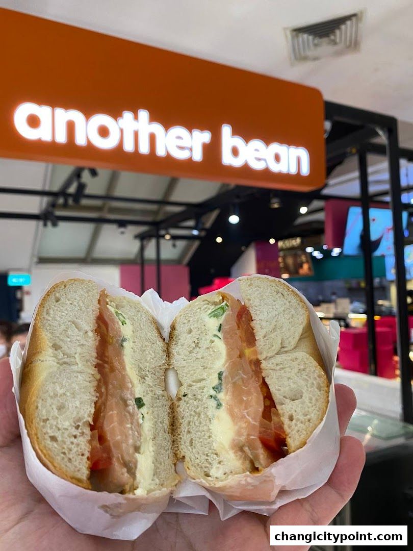 A hand holds a delicious salmon and cream cheese bagel from Another Bean.