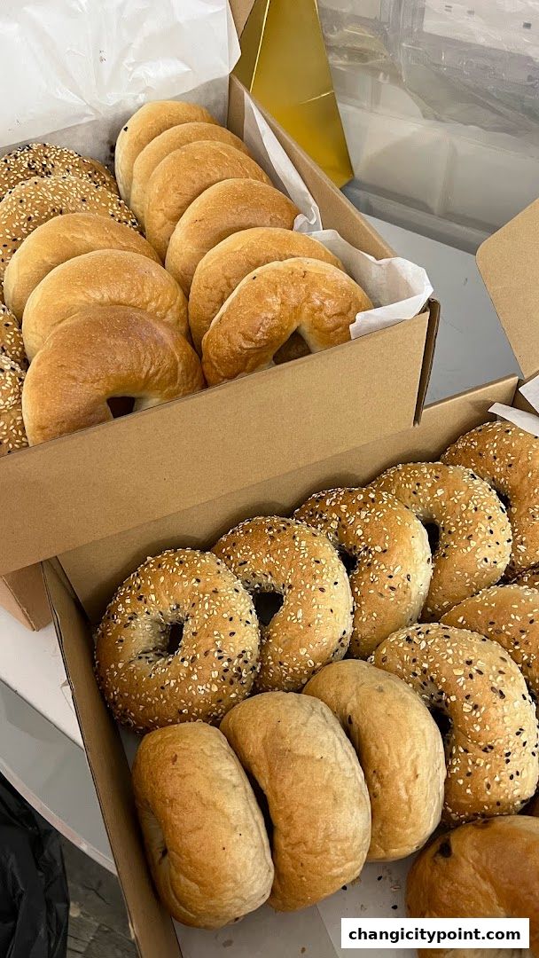Two boxes filled with freshly baked bagels, some plain and some topped with sesame and black seeds.