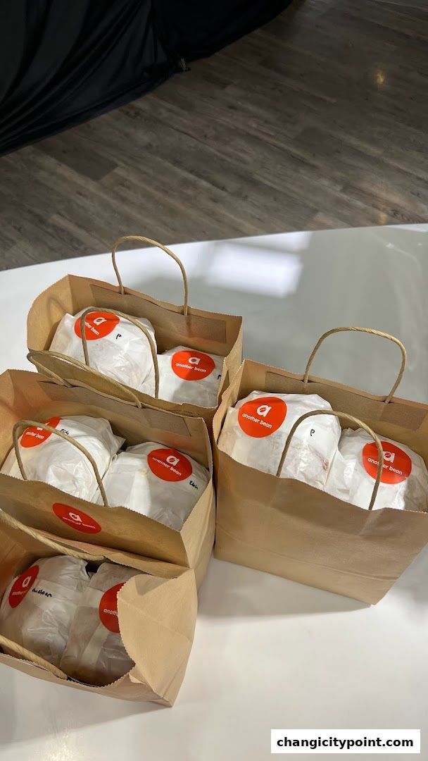 Several brown paper bags from 'another bean' filled with wrapped food items.