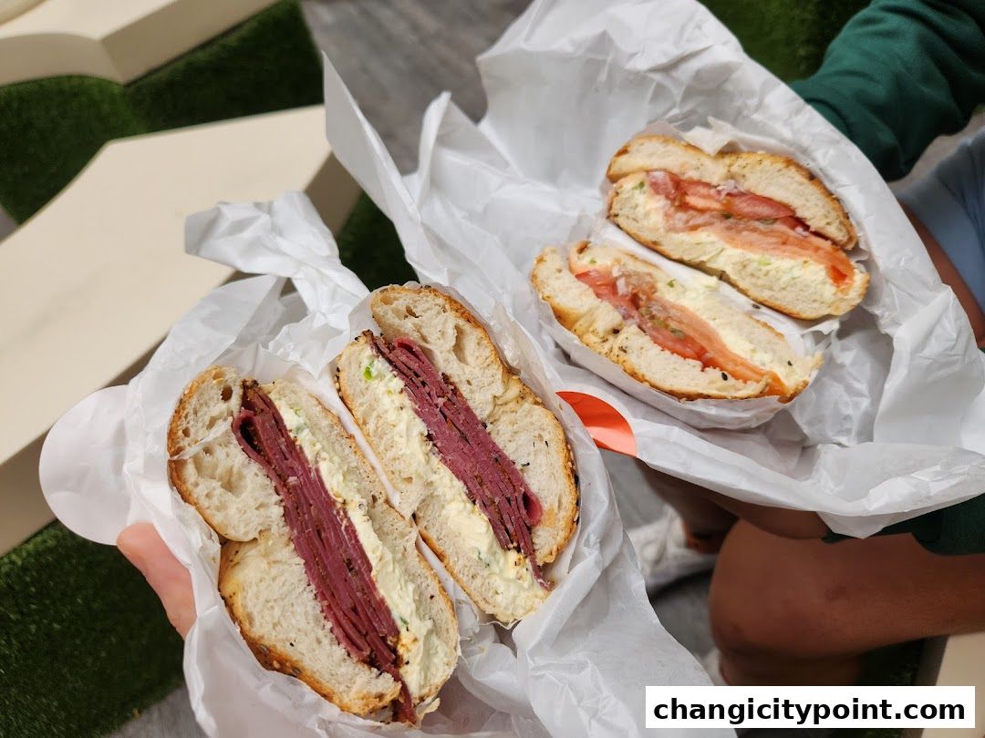 Two delicious bagels, one with pastrami and cream cheese, the other with salmon and cream cheese.