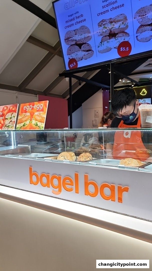 A bagel bar counter with a digital menu displaying bagel options and prices.