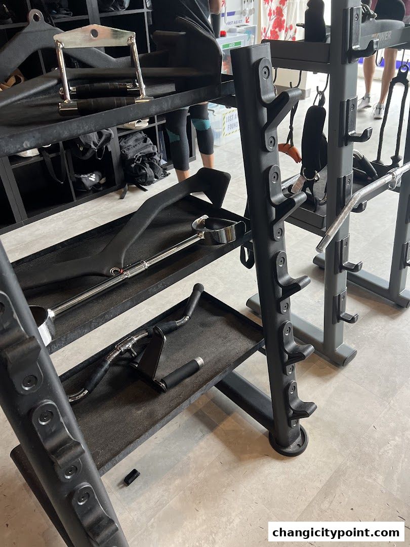 Gym equipment including weight racks, bars, and handles in a fitness center.