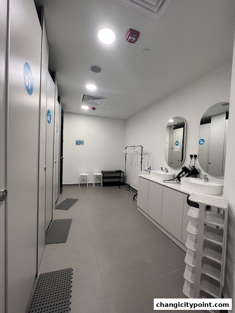 Interior view of a clean and modern gym locker room with private stalls and vanity area.