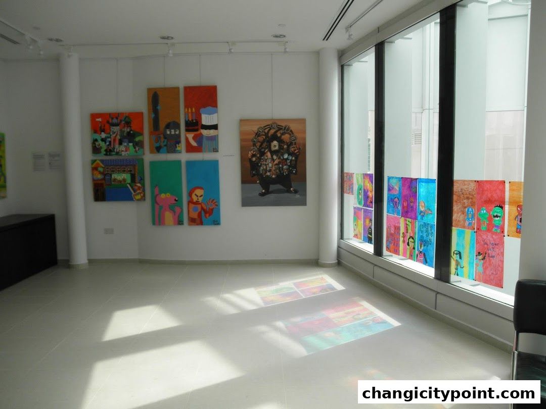 Interior view of an art gallery showcasing colorful paintings and drawings displayed on walls and windows.