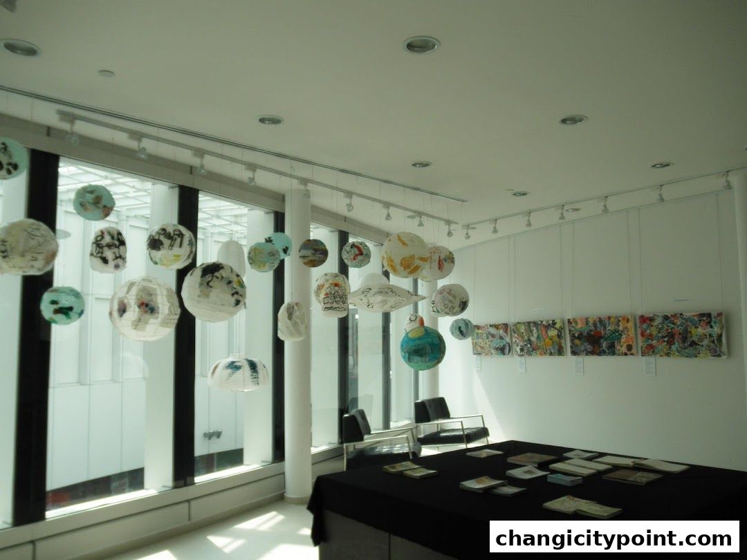 An art exhibition featuring hanging paper lanterns and wall art, with a display table.
