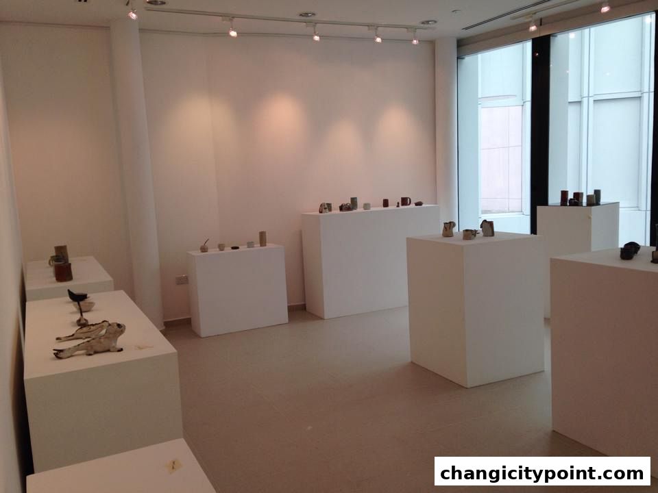 An art gallery interior with various ceramic pieces displayed on white pedestals.