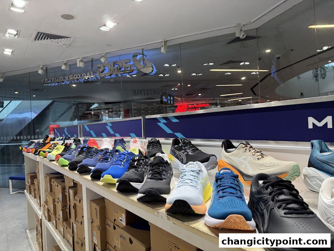 A display of various ASICS running shoes on shelves in a retail store.