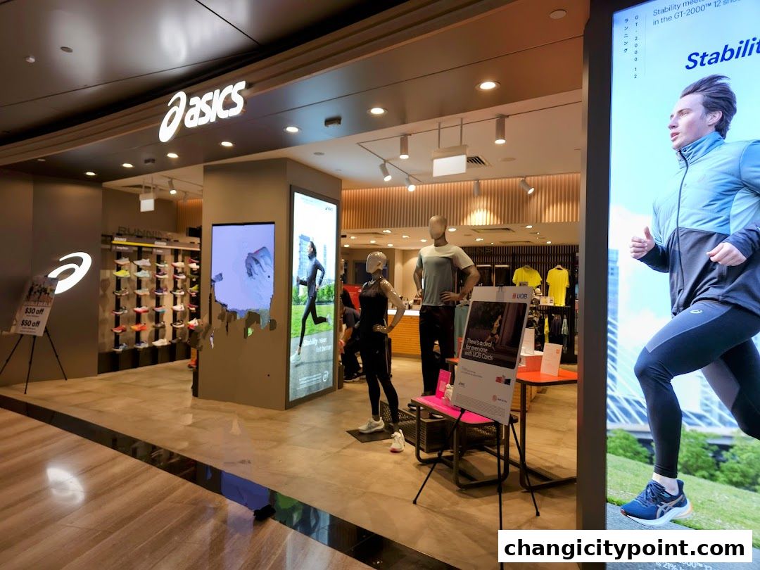 The entrance of an ASICS outlet store showcasing running shoes and apparel with promotional signage.