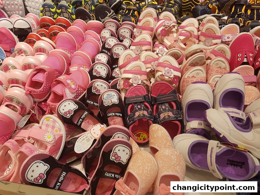 A colorful display of children's shoes, featuring sandals and closed-toe shoes in various pink and white designs.