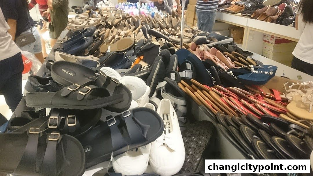 A wide selection of sandals, flip-flops, and shoes displayed on tables inside a Bata store.
