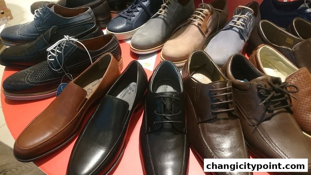 A variety of men's dress shoes and loafers are displayed on a red surface.