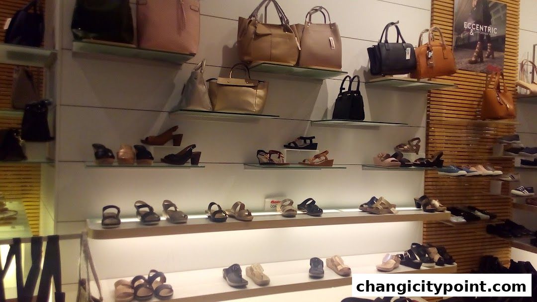 A well-lit display of various shoes and handbags on shelves in a retail store.