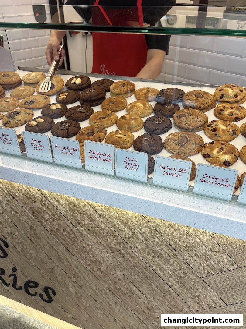 A display of various freshly baked cookies with labels indicating their flavors.