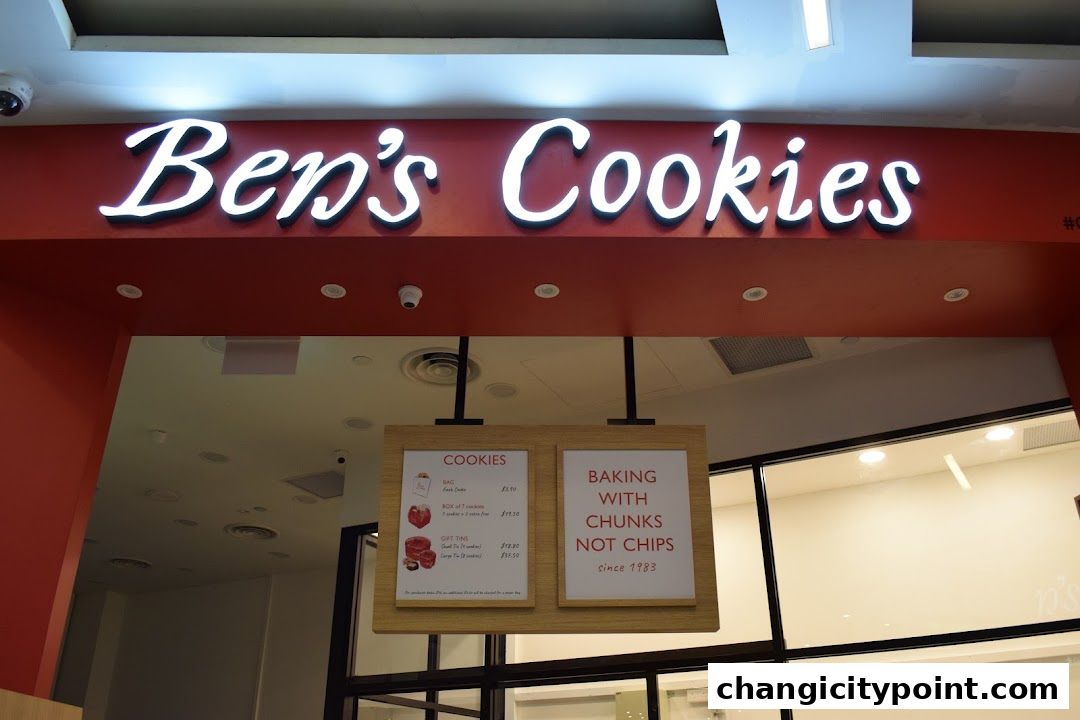 The illuminated sign for Ben's Cookies above the shop entrance with a menu board.
