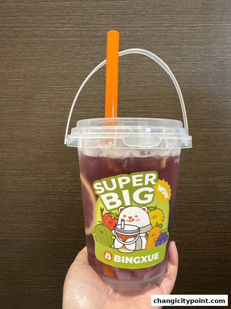 A hand holds a large cup of purple beverage with fruit illustrations and the BingXue logo.