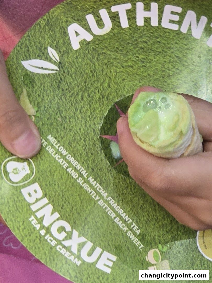 A hand holds a matcha-flavored ice cream cone with the BingXue logo visible.