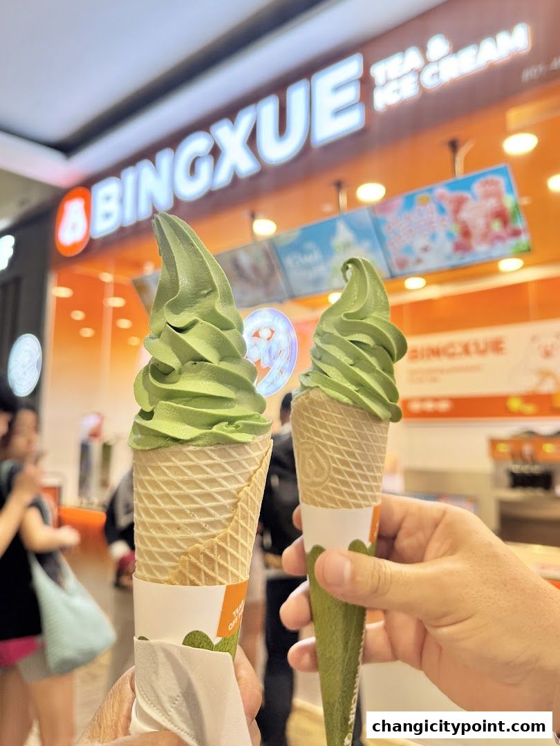 Two matcha ice cream cones held up in front of the BingXue Tea & Ice Cream shop.