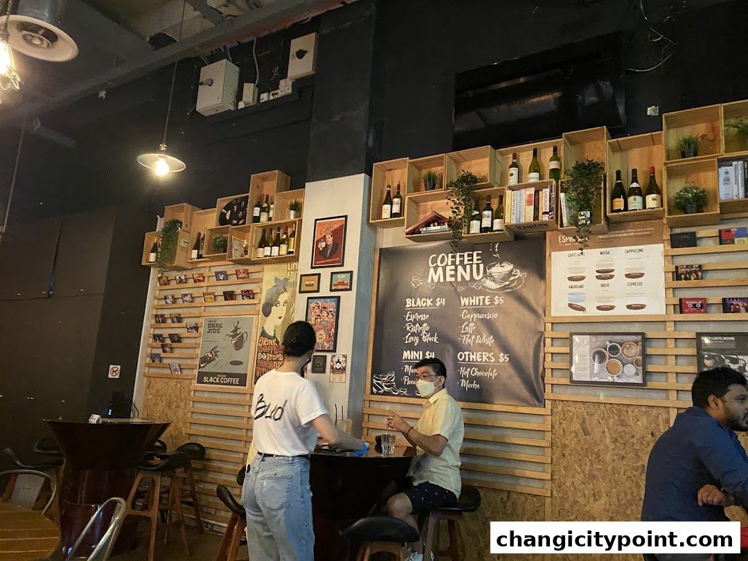 Interior of a coffee shop with a menu board and patrons at tables.