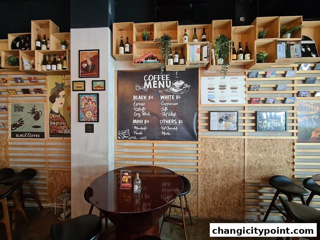Interior of a coffee shop with a menu board, wooden shelves, and seating.