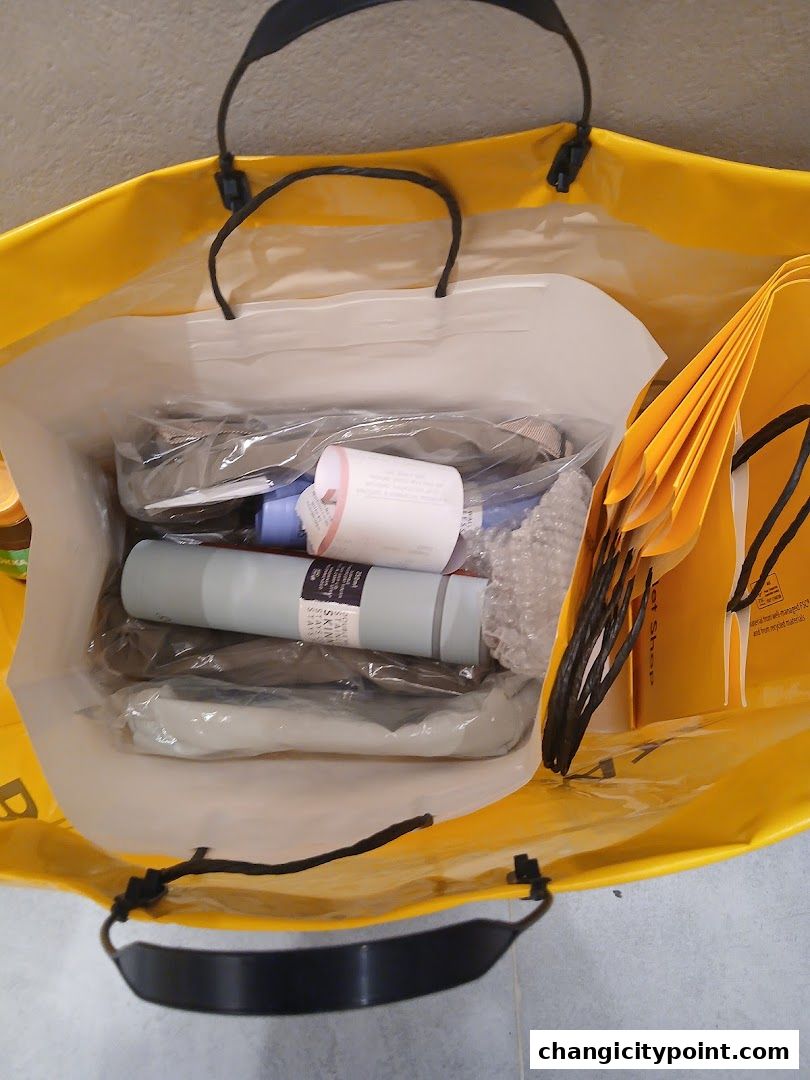 A bright yellow shopping bag filled with various items and smaller bags.