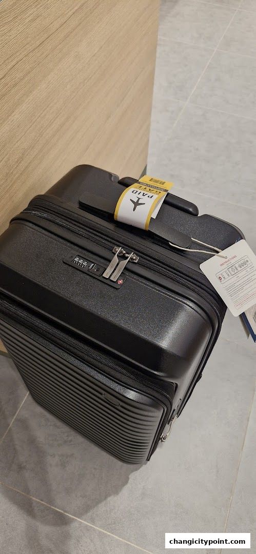 A black suitcase with a 'PAID' tag and an airplane icon rests on a tiled floor.