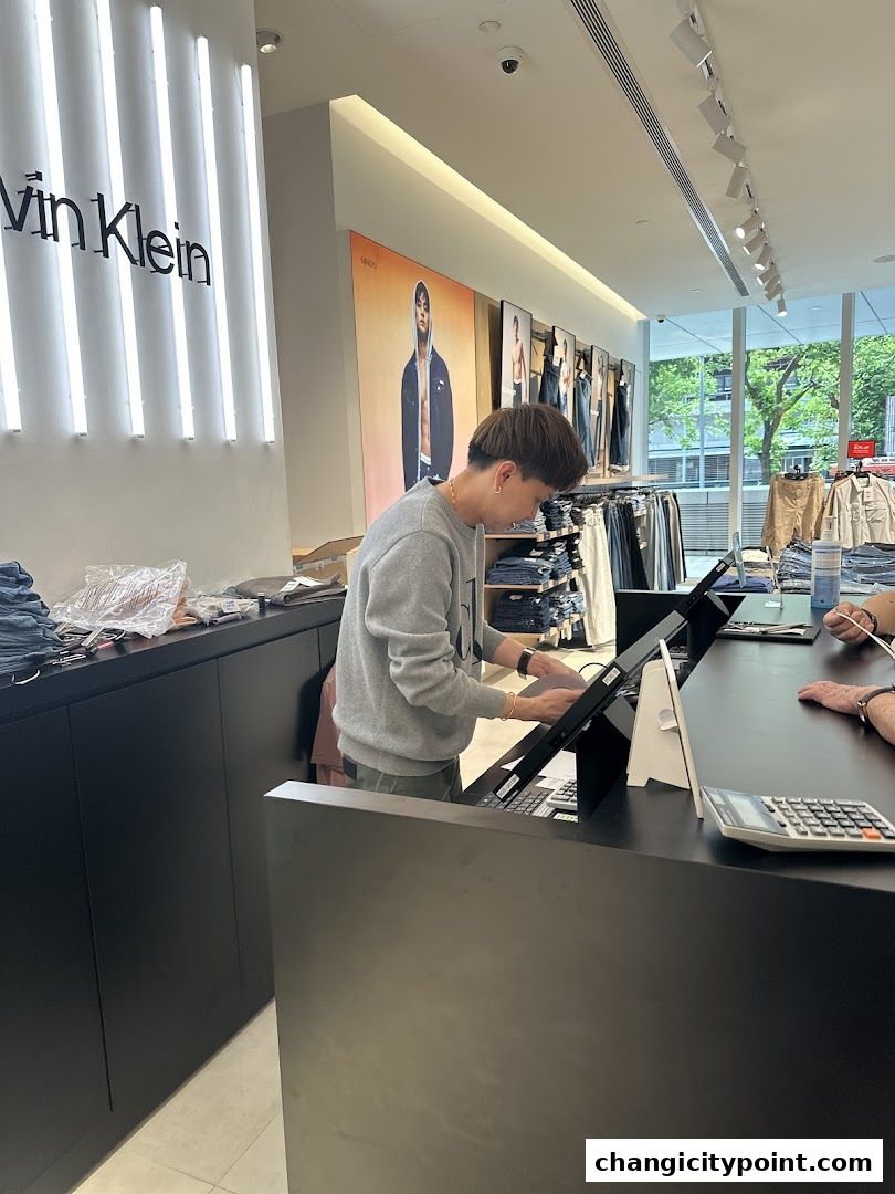 A Calvin Klein store interior with a cashier at the counter and clothing displays.