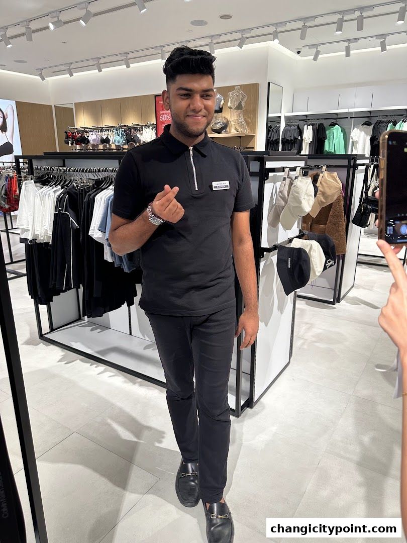 A man in a black polo shirt and pants poses in a Calvin Klein store.