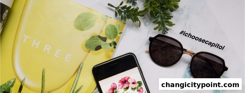 A flat lay featuring sunglasses, a smartphone, and a magazine with the word 'THREE'.