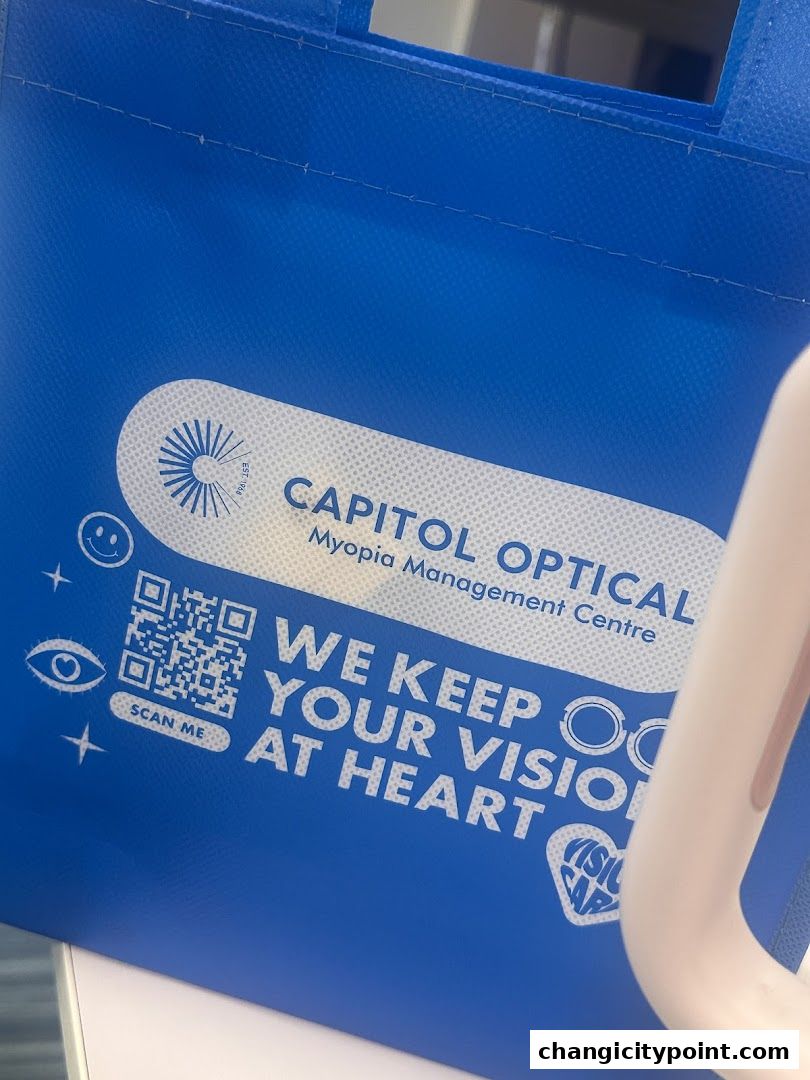 A blue reusable bag with Capitol Optical branding and a QR code.