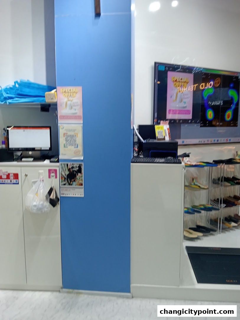 A retail shop interior displaying shoes, a computer monitor, and a large screen showing foot pressure analysis.