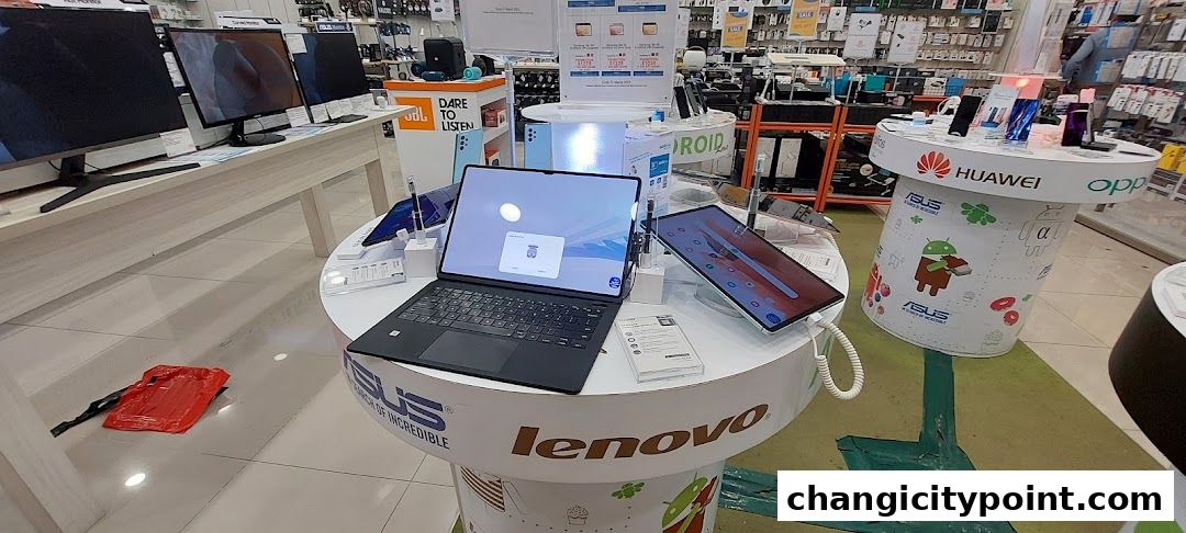 A retail store display featuring laptops, tablets, and monitors from various brands.
