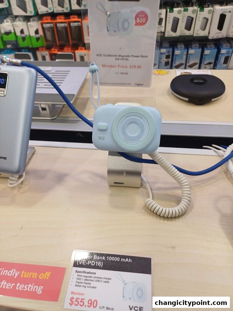 A light blue power bank shaped like a camera is displayed on a wooden counter.