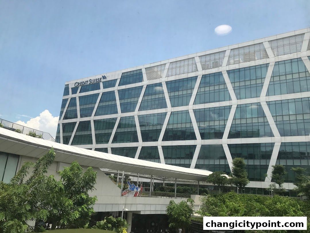 Modern office building with geometric facade and surrounding greenery.