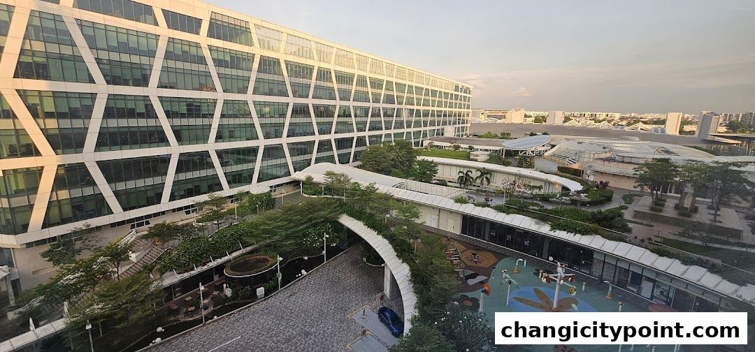 Aerial view of Changi City Point carpark and surrounding buildings with greenery and a playground.