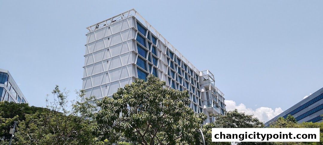Modern office buildings with trees in the foreground under a clear blue sky.