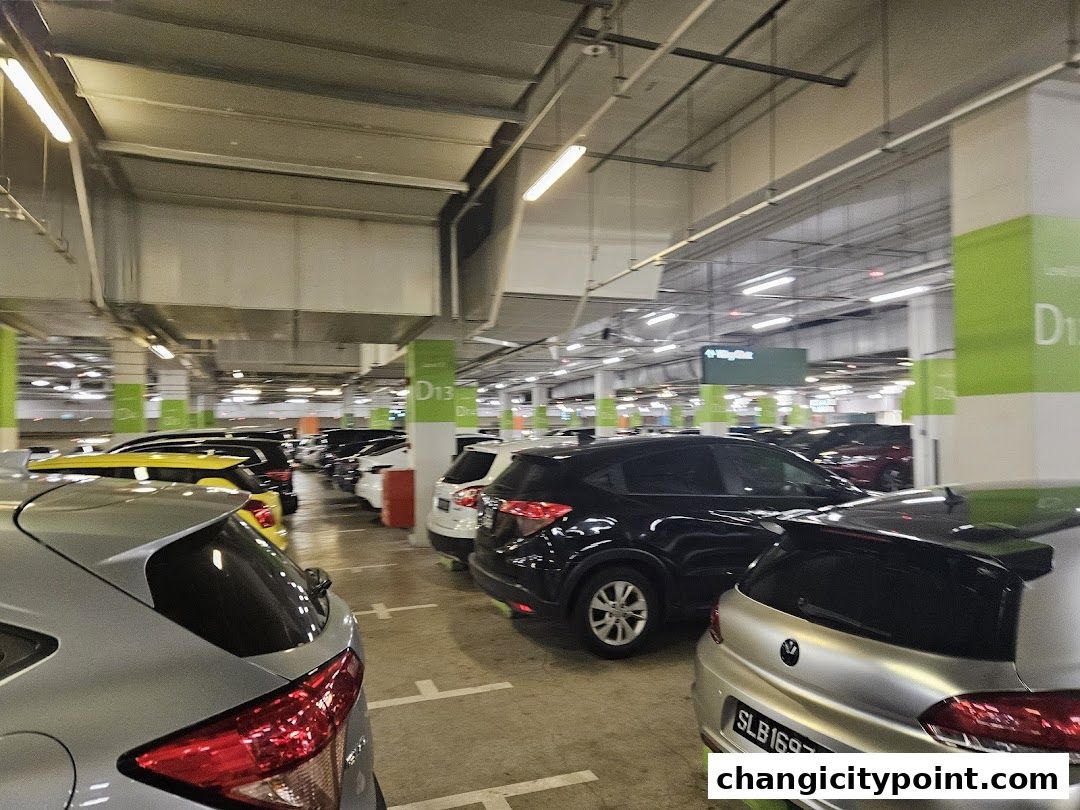 A multi-level carpark with many cars parked, illuminated by fluorescent lights.