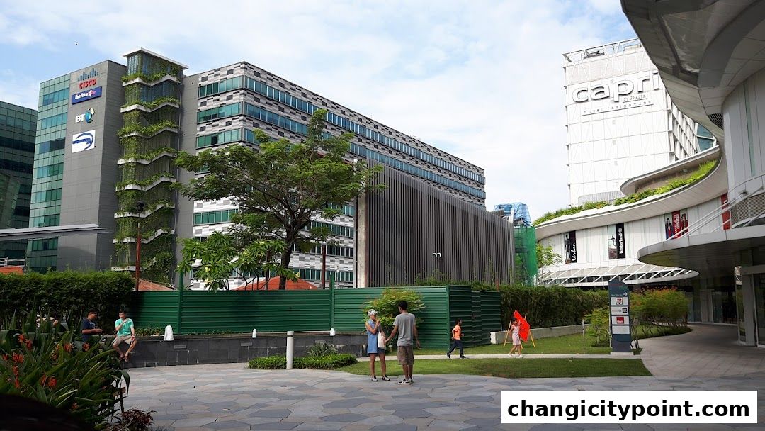 People in a plaza with modern buildings and greenery.