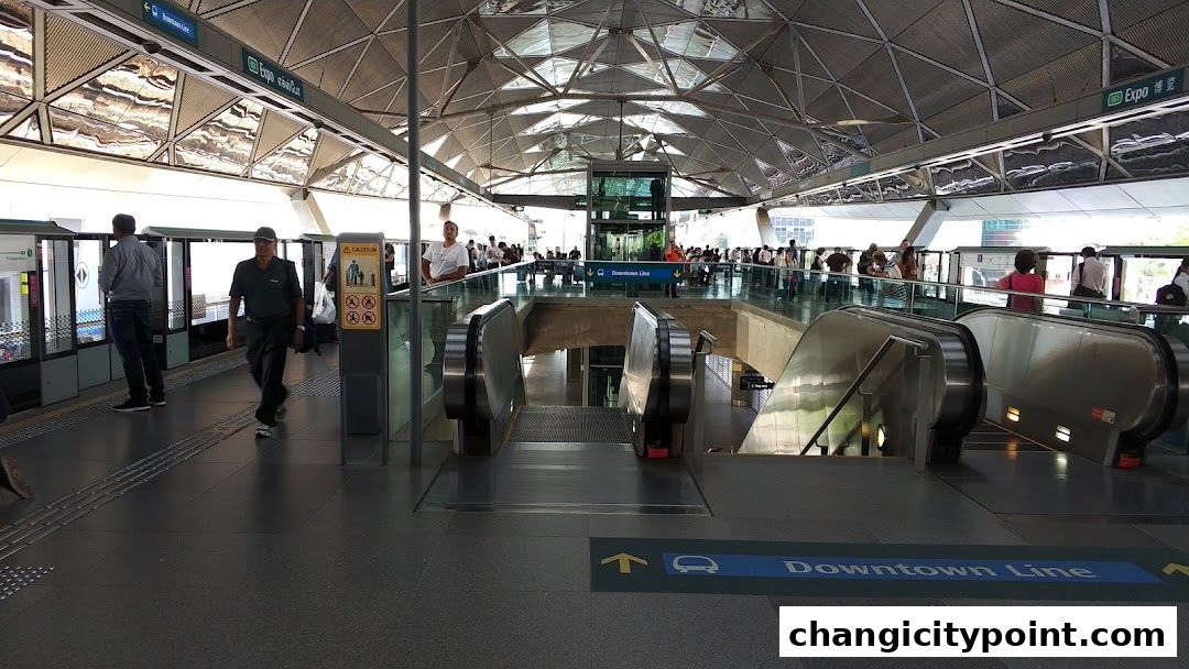 A busy train station platform with escalators and people waiting.