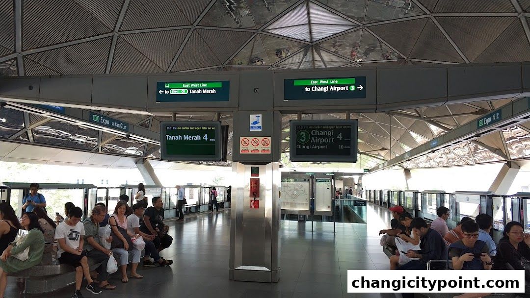 People waiting at a train station platform with digital signs indicating destinations.